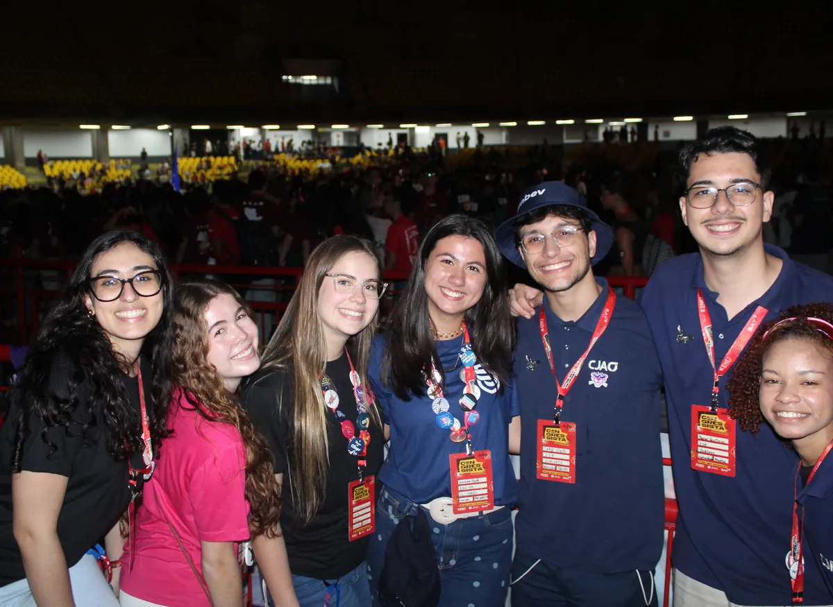 Oito membros da CJA, a maioria de polo azul-marinho, sorrindo lado a lado num evento à noite